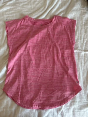 Rosa träningstopp från SOC - Säljer en rosa topp från SOC i storlek 158-164. Toppen har ett diskret randigt mönster och är tillverkad i mjuk polyester, perfekt för träning. Modellen är ärmlös med rundad hals och har en lätt loose passform som gör den skön att bära.