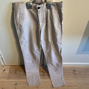 Beige tapered linnebyxor Jack & Jones - Snygga beige linnebyxor från Jack & Jones Pants Studio med tapered fit. Byxorna har klassiska sidfickor, bakfickor med knapp och bälteshällor. Perfekt för dig som gillar en stilren och avslappnad look. Materialet är linne och bomull för extra komfort. Nypris 600 sek