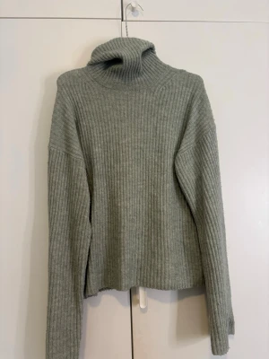 grön ribbad polotröja från H&M XS - Säljer en grön ribbstickad polotröja från H&M i storlek XS. Tröjan har lång ärm, hög polokrage och är tillverkad i mjukt stickat material. Perfekt för kyliga dagar och enkel att styla med jeans eller kjol.
