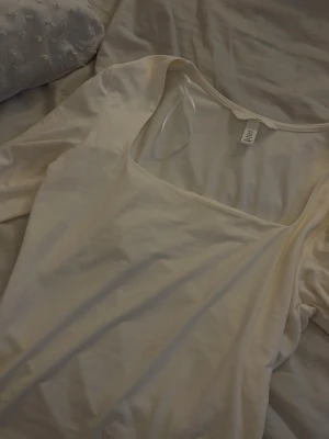 Vit långärmad topp med fyrkantig hals - Säljer en stilren vit långärmad topp från H&M med snygg fyrkantig halsringning. Toppen är gjord i mjuk bomull. Använd 2 gånger endast. 