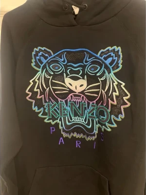 KENZO - Holiday Capsule Limited Edition Tiger Hoodie - Självklart äkta, photon på lappar/sömmar osv kan skickas om så önskas. Tröjan är av märket KENZO, modell: Holiday Capsule Limited Edition Tiger Hoodie. Nypris ligger runt 5-7.500kr. (Köptes ny för 6.499kr).  Tröjjan är endast använd några fåtal gånger då den tyvär är en storlek för liten för mig. (Tröjjan till SALU är strk L)