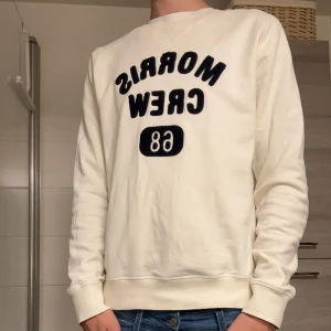 Morris tröja  - Säljer en vit sweatshirt från Morris med mörkblått broderat tryck 'Morris Crew 68' på bröstet. Tröjan har rund halsringning, långa ärmar och är tillverkad i mjuk bomull. Perfekt för en chill och stilren look.