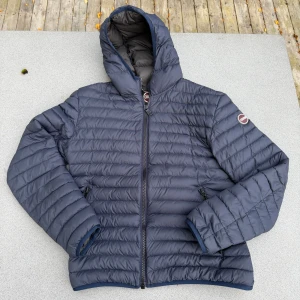 Mörkblå Colmar pufferjacka med huva - Säljer en mörkblå pufferjacka från Colmar med huva och dragkedja framtill. Jackan har quiltad design, två fickor med dragkedja och Colmar-logga på ärmen. Storleken är 52 och är perfekt för kyliga dagar ❄️, och  en riktigt snygg passform. Bilderna passade inte in i plick så bra så man ser inte hela bilden men hoppas de funkar ändå. Köpte den för runt 3000-4000 för nått år sedan, inga synliga defekter på den. 🍂🍁