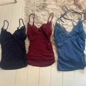 3 spetslinnen i marinblått, vinrött och blått - Jag har lagt upp en till annons där det är fri frakt till 13 oktober ! Säljer tre snygga linnen med spetsdetaljer vid bysten, Alla för 150kr. Ett marinblått, ett vinrött och ett blått linne, alla med smala axelband och v-ringad spetskant. Perfekta att styla lager på lager eller som de är för en trendig look.