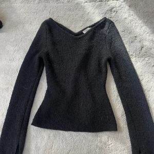 Svart stickad tröja med v-ringning - Svart stickad tröja med snygg v-ringad hals och lång ärm. Modellen är figurnära och har en lite ruff struktur i materialet. Inte sticksig