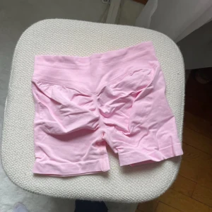 Ljusrosa seamless biker shorts - Säljer ett par ljusrosa seamless biker shorts med hög midja. De är stretchiga och har en scrunch-detalj bak för extra form. Perfekta för träning eller bara att chilla i. Materialet känns mjukt och följsamt mot huden.