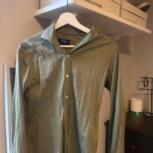Grön skjorta från Eton, slim fit XS - Snygg grön skjorta från Eton i slim fit med klassisk krage och vita knappar. Skjortan är långärmad och har en stilren look som passar perfekt till jeans eller chinos. Tillverkad i mjuk bomull för en skön känsla hela dagen. Priset går alltid att diskutera!