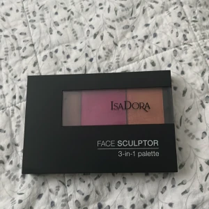 IsaDora Face Sculptor 3-in-1 palette - IsaDora Face Sculptor 3-in-1 palette. Paletten innehåller tre nyanser: en varm brun contour, en plommonrosa blush och en champagnefärgad highlighter. Perfekt för att skulptera och framhäva ansiktet. Använd endast EN GÅNG, därav i mycket bra skick.