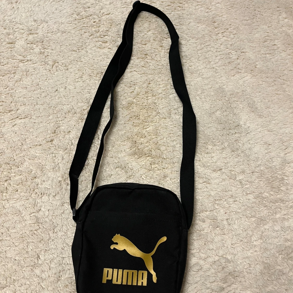 Svart axelväska från Puma med guldlogo