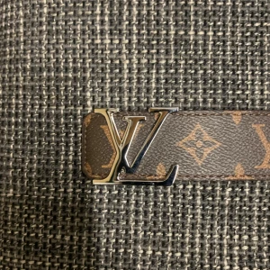 Louis Vuitton Monogram Skärp 110/44 - Säljer ett klassiskt Louis Vuitton skärp i brunt skinn med ikoniskt monogrammönster och silverfärgat LV-spänne. Bältet har exklusiv känsla och tydlig logga på spännet samt präglad märkning på insidan. Perfekt accessoar för att lyfta din outfit.
