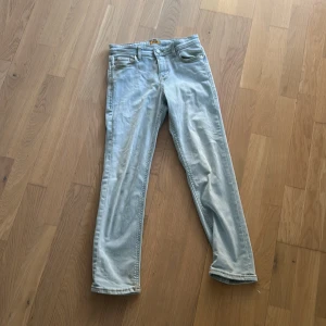 Ljusblå jeans från Jack & Jones - Säljer ett par ljusblå jeans från Jack & Jones, modell Regular Clark. Klassisk femficksdesign, raka ben och snygga kontrastsömmar. Jeansen är i bomull och har en bekväm passform som funkar till många olika stilar. Ny pris 600kr