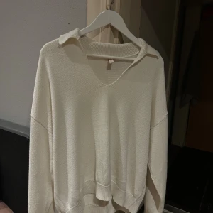 Vit stickad v-ringad tröja med krage - Säljer en vit stickad tröja med v-ringning och snygg krage. Tröjan har lång ärm och avslappnad passform