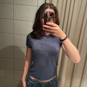 Mörkblå basic t-shirt i bomull - En enkel och stilren mörkblå t-shirt. Modellen är figurnära med korta ärmar och rund halsringning. Perfekt till jeans eller shorts.