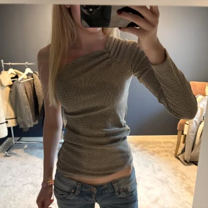 topp från Zara - Säljer en grå ribbad topp från Zara med oneshoulder-design och lång ärm. Änvänd 1 gång