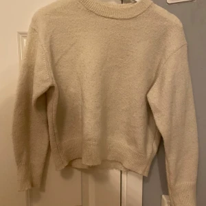 Beige stickad tröja från Gina Tricot - Mysig beige stickad tröja från Gina Tricot med rund halsringning och ribbade muddar. Perfekt för lager-på-lager och passar till allt. Enkel och stilren design som är lätt att matcha med dina favoritjeans eller kjol.