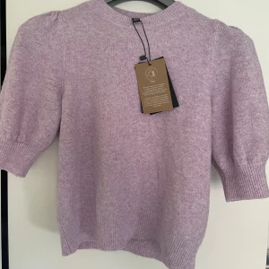 Ljuslila stickad tröja med puffärm - Superfin ljuslila stickad tröja med korta puffärmar och ribbade muddar.