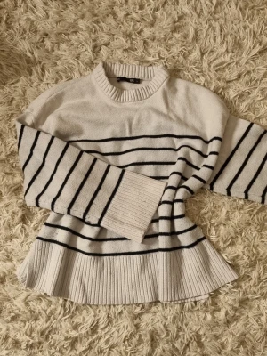 Vit stickad tröja med svarta ränder - Säljer en vit stickad tröja från H&M med svarta horisontella ränder. Tröjan har rund halsringning, långa ärmar och bred ribbstickad kant nedtill och vid ärmsluten. Perfekt för en avslappnad och trendig look.