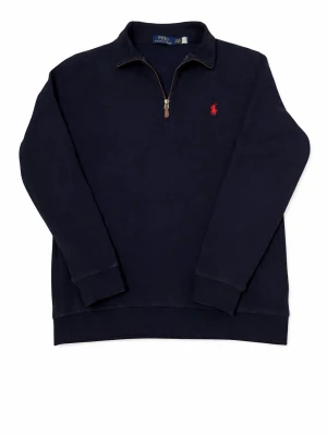 Marinblå halvzip från Polo Ralph Lauren - Mörkblå tröja med halv dragkedja från Polo Ralph Lauren. Klassisk design med röd broderad logga på bröstet och ståkrage.