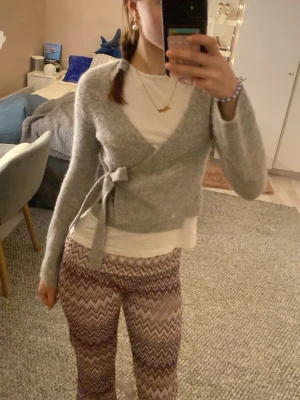 Grå sticksd knytkofta från Gina - Är XS men sitter som XXS! Små defekter på det stickade tyget men knappt något som syns 💗 Säljer eftersom den är för liten för mig!💕