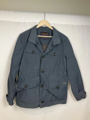 Woolrich Jacka  - Tja säljer en snygg blå jacka från Woolrich med krage och detaljer som knappar framtill. Jackan är i väldigt fint skick och säljs för endast 1399kr. Nypris över 6000kr. Skriv vid frågor eller ifall du vill ha fler bilder. Storlek Large.