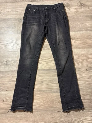 Sumwon Flared Jeans - Snygga svarta Sumwon flared jeans med slitna, råa benslut och klassisk femficksdesign. Jeansen har en rak passform och subtila slitningar framtill för en cool, avslappnad look. Perfekta för dig som gillar en edgy stil.