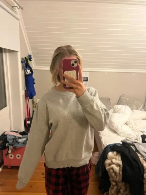 Grå basic sweatshirt - Enkel och stilren grå sweatshirt med rund halsringning och ribbade muddar vid ärmslut och nederkant. Perfekt för en avslappnad look och lätt att matcha med andra plagg. Mjuk och bekväm bomullsblandning.