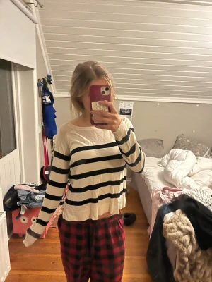 Vit och svart randig stickad tröja - Snygg stickad tröja i vitt med svarta horisontella ränder. Tröjan har en avslappnad passform, rund halsringning och långa ärmar. Perfekt för en chill och trendig look.