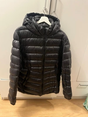 Svart dunjacka från Colmar  - Snygg svart dunjacka. Jackan har quiltad design och Colmar-logga på ärmen. Perfekt för kalla dagar och enkel att matcha med olika outfits. Storlek 56 sitter som XL