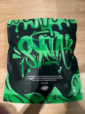 Beige set med rosa graffiti-tryck - Säljer ett beige underklädesset från SNAH med coolt rosa graffiti-tryck på både tröja och shorts. Tröjan har korta ärmar och rund hals, shortsen har dragsko i midjan för skön passform. Perfekt för dig som gillar streetwear och unika prints.