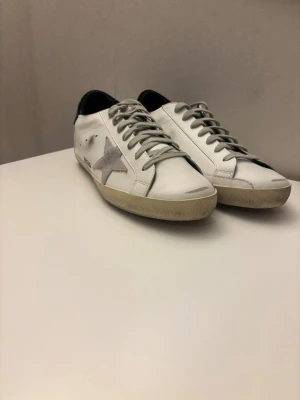 Vita Golden Goose sneakers med stjärna - Snygga vita sneakers från Golden Goose med grå mockadetaljer.