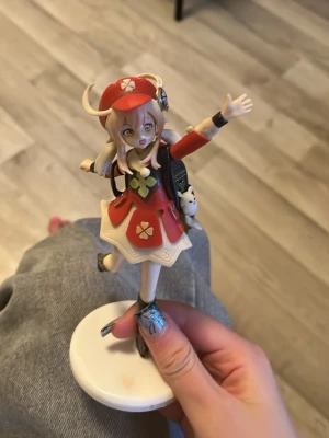Klee cosplay figur från Genshin Impact - Detaljerad cosplayfigur av Klee från Genshin Impact. Hon har röd klänning med vita och blommiga detaljer, röd hatt med horn, ryggsäck och svarta stövlar. Perfekt som accessoar till maskerad eller cosplay. Materialet är hårdplast.