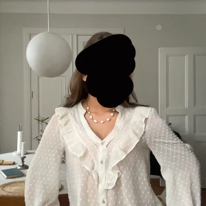 Vit blus Zara  - Söt vit trendig blus med volangdetaljer längs V-ringningen och små diskreta prickar i tyget. Nyskick 