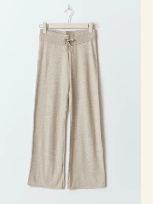 Beige mjukisbyxor med snörning stickade - Mysiga beige mjukisbyxor med bred resår i midjan och snörning framtill. Byxorna har en loose passform och raka, vida ben som ger en avslappnad look. Perfekta för chill dagar hemma eller när du vill vara bekväm men ändå se snygg ut.