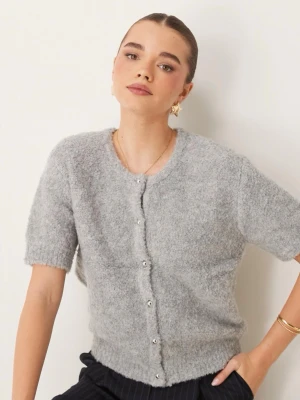 Grå fluffig kofta från Gina Tricot - Mysig grå kofta från Gina Tricot med kort ärm och fluffig textur. Koftan har rund halsringning och knäpps framtill med små pärlknappar.