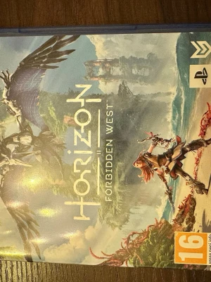 Horizon Forbidden West PS5 spel - Säljer Horizon Forbidden West till PS5, ett actionäventyrsspel med öppen värld där du spelar som Aloy. Omslaget har en färgstark illustration med futuristiska robotar och naturmiljöer. Spelet kommer i ett blått plastfodral.