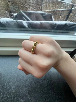Guldig ring med nitar - Cool ring i guldfärgad metall med markerade nitar runt hela bandet. Ringen har en edgy och modern design som sticker ut och passar perfekt för dig som gillar statement-smycken. Ingen synlig märkning på ringen, vet inte storlek men får plats på mitt ringfinger så den är kanske S/M!💘