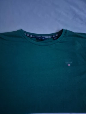 Mörk grön GANT t-shirt - Säljer en GANT t-shirt i strl XS eller 164. Nytvättad och ren!