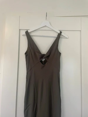 Skogsgrön klänning - Snygg beige långklänning med twistad detalj framtill och v-ringad hals. Aldrig använd!!