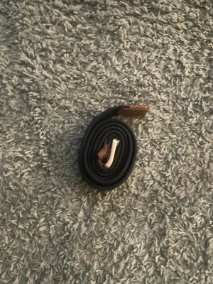 Svart flätat bälte med läderdetaljer - Snyggt blått flätat bälte med bruna läderdetaljer och silvrigt spänne. Perfekt accessoar för att lyfta din outfit. Bältet är flexibelt och passar till både jeans och chinos. Bältet är från jack&jones. 120cm långt