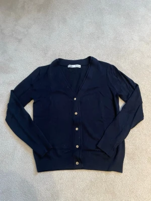 Mörkblå cardigan från Zara - Stilren mörkblå cardigan från Zara med v-ringning och knappar framtill. Långärmad modell i tunt, mjukt material som passar perfekt till lager på lager. Klassisk och enkel design som funkar till det mesta. ❕Aldrig använd❕