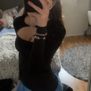 Svart långärmad topp med cut out - Säljer en svart långärmad topp med snygg cut out-detalj över bröstet. Toppen är tight och har en modern, stilren look som passar perfekt till jeans eller kjol. Materialet känns stretchigt och bekvämt.