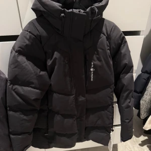 Svart dunjacka Sail Racing W Patrol - Svart dunjacka från Sail Racing, modell W Patrol Down Jacket. Jackan har hög krage, huva och flera dragkedjeförsedda fickor framtill. Perfekt jacka för dig som fryser under vintern och vill ha en skön och varm jacka. Nypris på jackan är 3500kr den har aldrig varit använd och har kvar sin etikett. Priset jag lägger ut är 2600kr men priset är inte hugget i sten. Så via snabbaffär kan jag sänka priset lite.
