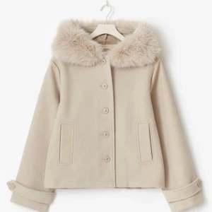 Beige kappa med fuskpäls-krage - Superfin beige kappa med stor fluffig fuskpäls-krage och knappar framtill. Jackan är croppad och har snygga detaljer vid ärmsluten. Perfekt för dig som vill ha en mysig och stilren look under höst och vinter.  Prislapp är kvar på jackan, använd minst 2  gånger, storlek xs men passar mej som har S  KÖPTES FÖR 500’