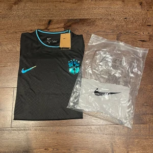Brasilien fotbollströja limited edition - Snygg svart Brasilien fotbollströja från Nike med blå detaljer och Brasilien-märke på bröstet. Tröjan har korta ärmar, rund hals och är tillverkad i ett lätt, ventilerande funktionsmaterial. Storlek S. Pris kan diskuteras!