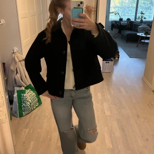 Svart kort rock med knappar - Säljer en svart kappa som sitter skit fint på älskar den och har bara använt den 3 gånger. Nu när det är höst så är den här jackan perfekt att ha.