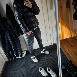 Svart Moncler Maya - Säljer en svart glansig pufferjacka från Moncler, modell Maya. Jackan har klassisk Moncler-logga på ärmen, dragkedja framtill och quiltad design. Perfekt för kalla dagar och riktigt snygg streetstil. Fodrad med dun för extra värme och har lång ärm. Jackan är i storlek 2 vilket motsvarar M