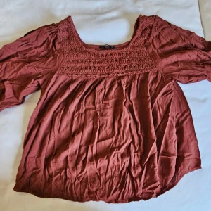 Rostbrun blus från ONLY med spets - Säljer en rostbrun blus från ONLY med vacker spets upptill och puffiga långärmar. Blusen har en rundad halsringning och är tillverkad i ett mjukt, lätt material som ger en skön och luftig känsla. Perfekt för dig som gillar boho-vibe och snygga detaljer.