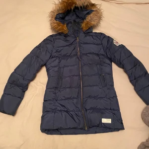 Mörkblå dunjacka Odd Molly  - Snygg mörkblå dunjacka från Odd Molly med broderad logga på ärmen och mysig huva med fuskpäls. Värmande till vintern.