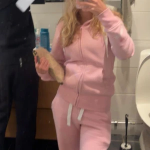 Russemerch sett rosa - Säljer ett par ljusrosa mjukisbyxor med vit snörning i midjan. Byxorna har en avslappnad passform och är perfekta för chill dagar. Tillverkade i mjukt material som känns skönt mot huden.