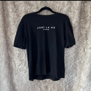 Svart t-shirt med tryck - Svart t-shirt med text på bröstet. B 49 cm, L 58 cm